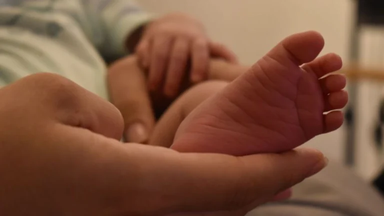 Mão de uma mãe segurando o pé do seu bebê